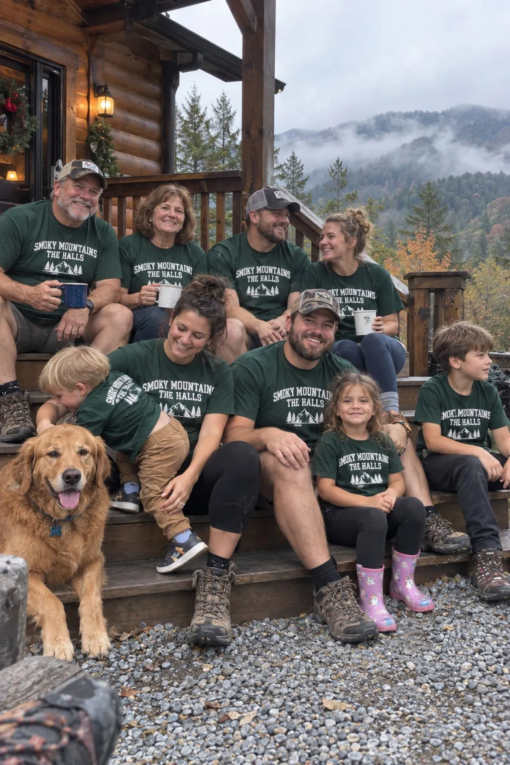 A family and their dog on the steps of a log cabin in green “Smoky Mountains, The Halls” shirts