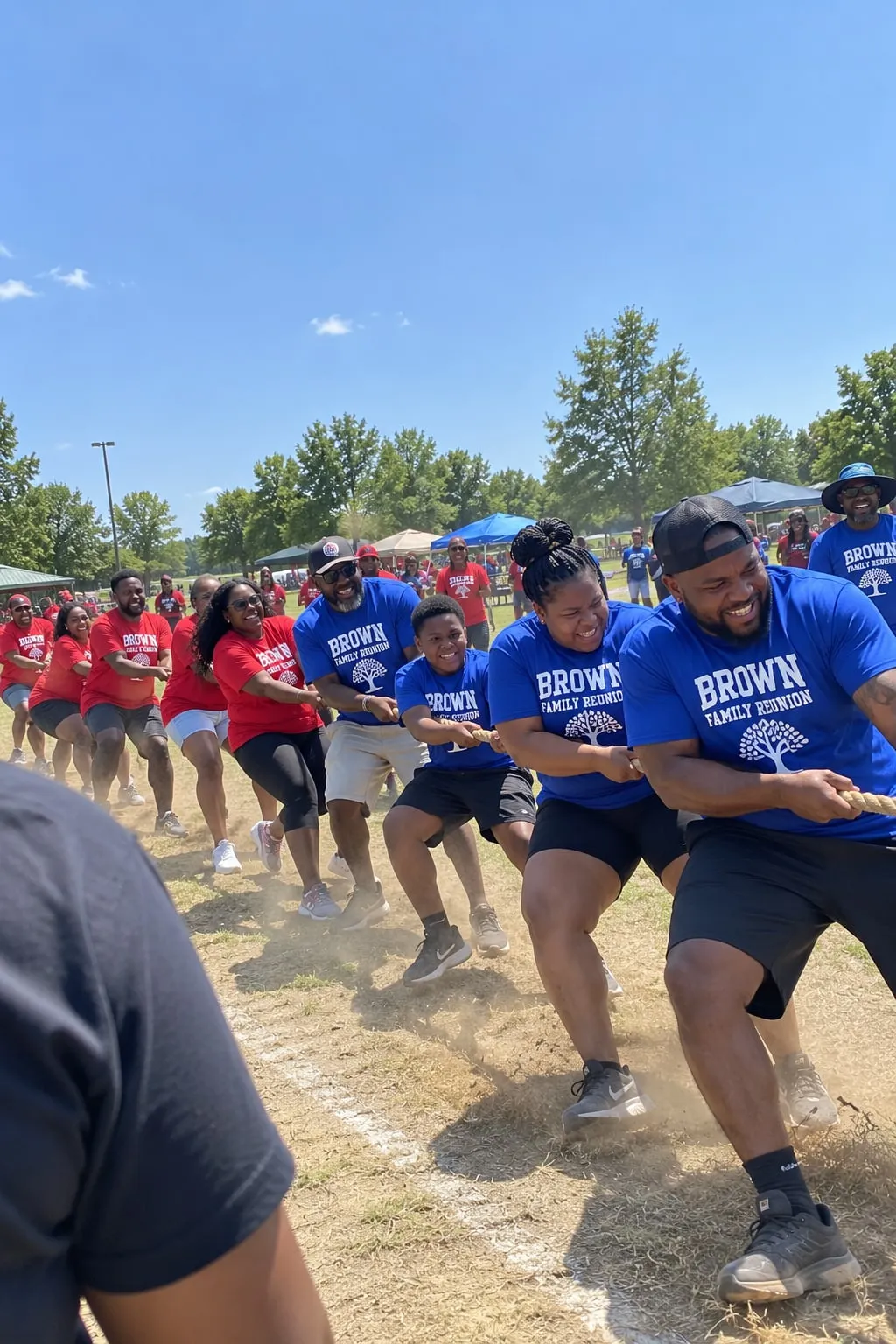 A family reunion tug-of-war between a team in red shirts and a team in blue “Brown Family Reunion” shirts