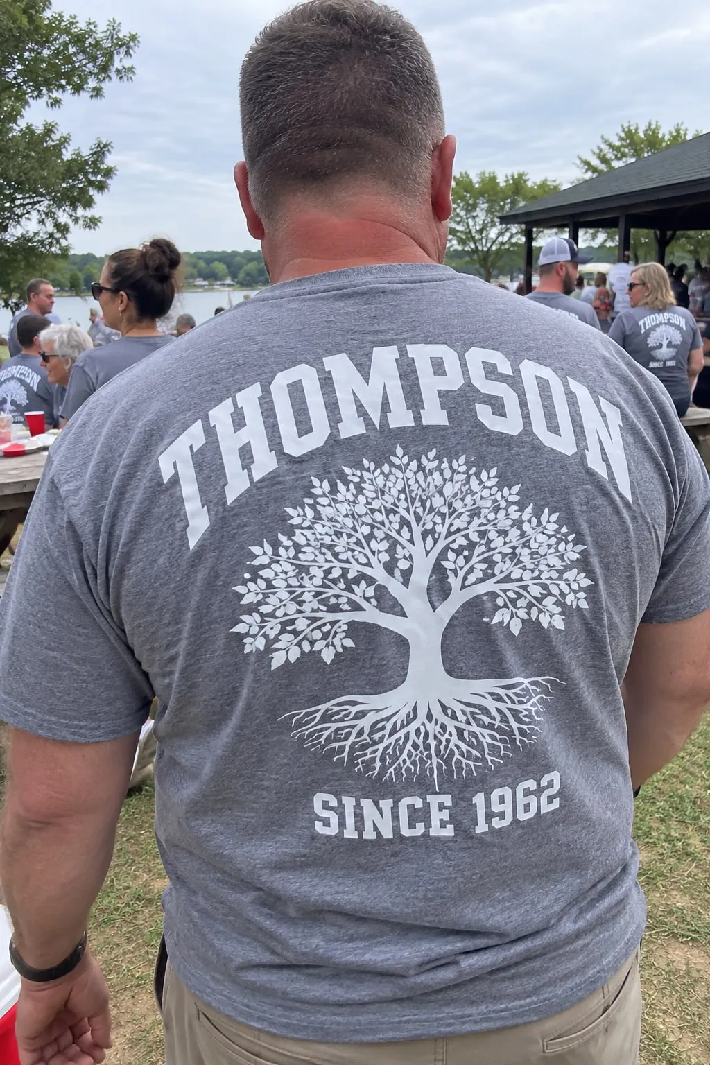 The back of a grey shirt with “Thompson” above a large white family tree with roots and “Since 1962” below